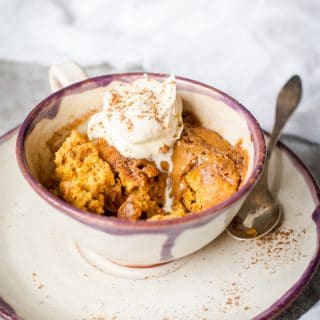 Side shot of Spiced pumpkin cake in a mug with cream on top
