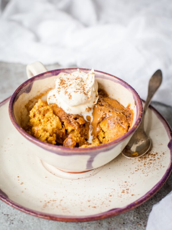 Side shot of Spiced pumpkin cake in a mug with cream on top