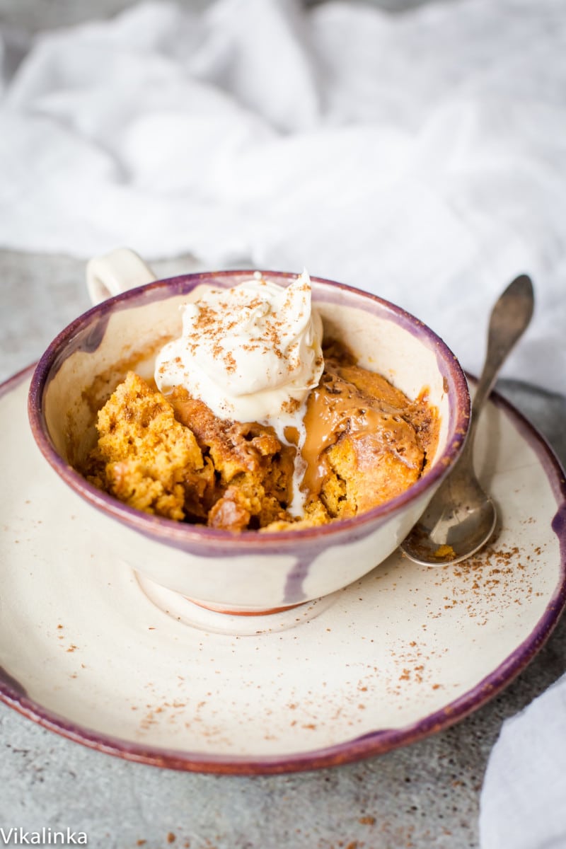 Side shot of Spiced pumpkin cake in a mug with cream on top