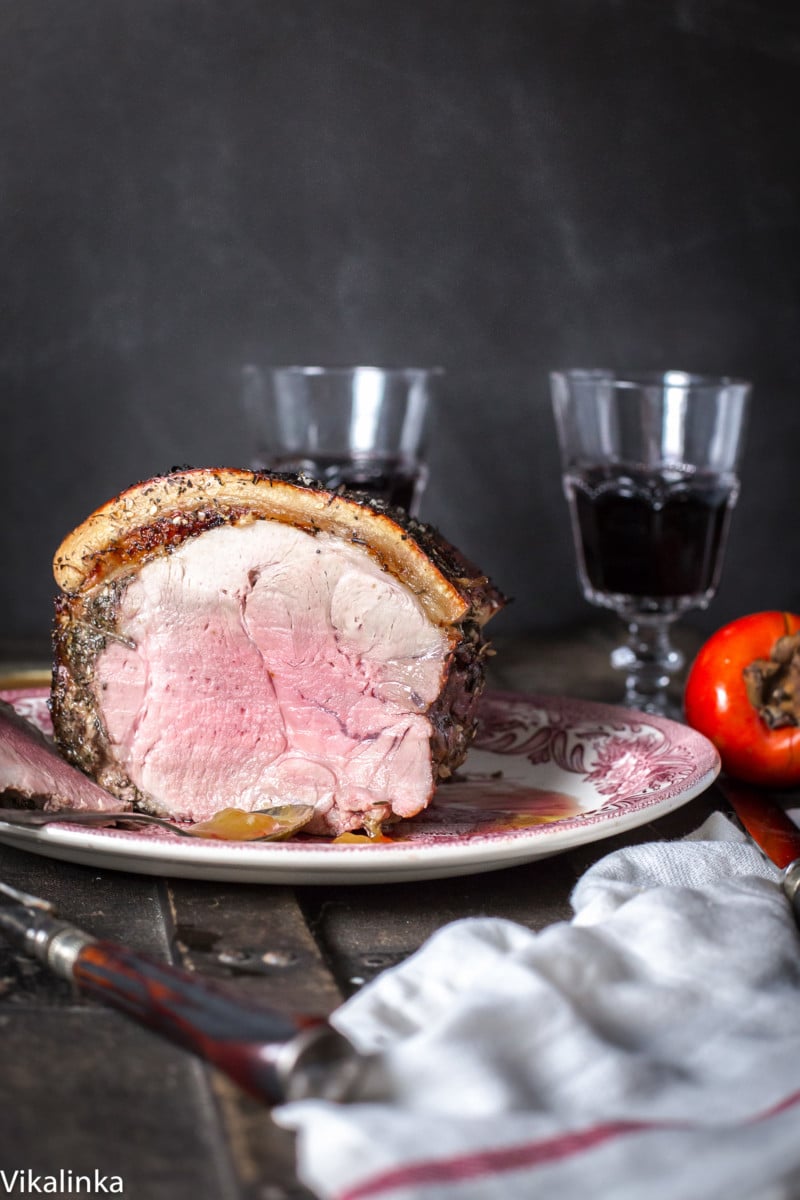 Pork roast cut open next to two glasses of wine