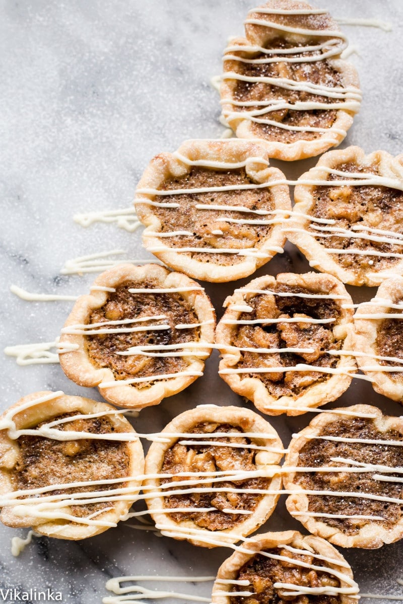 Butter Tarts-flaky pastry tartlets filled with delicious golden custard, raisins and walnuts.