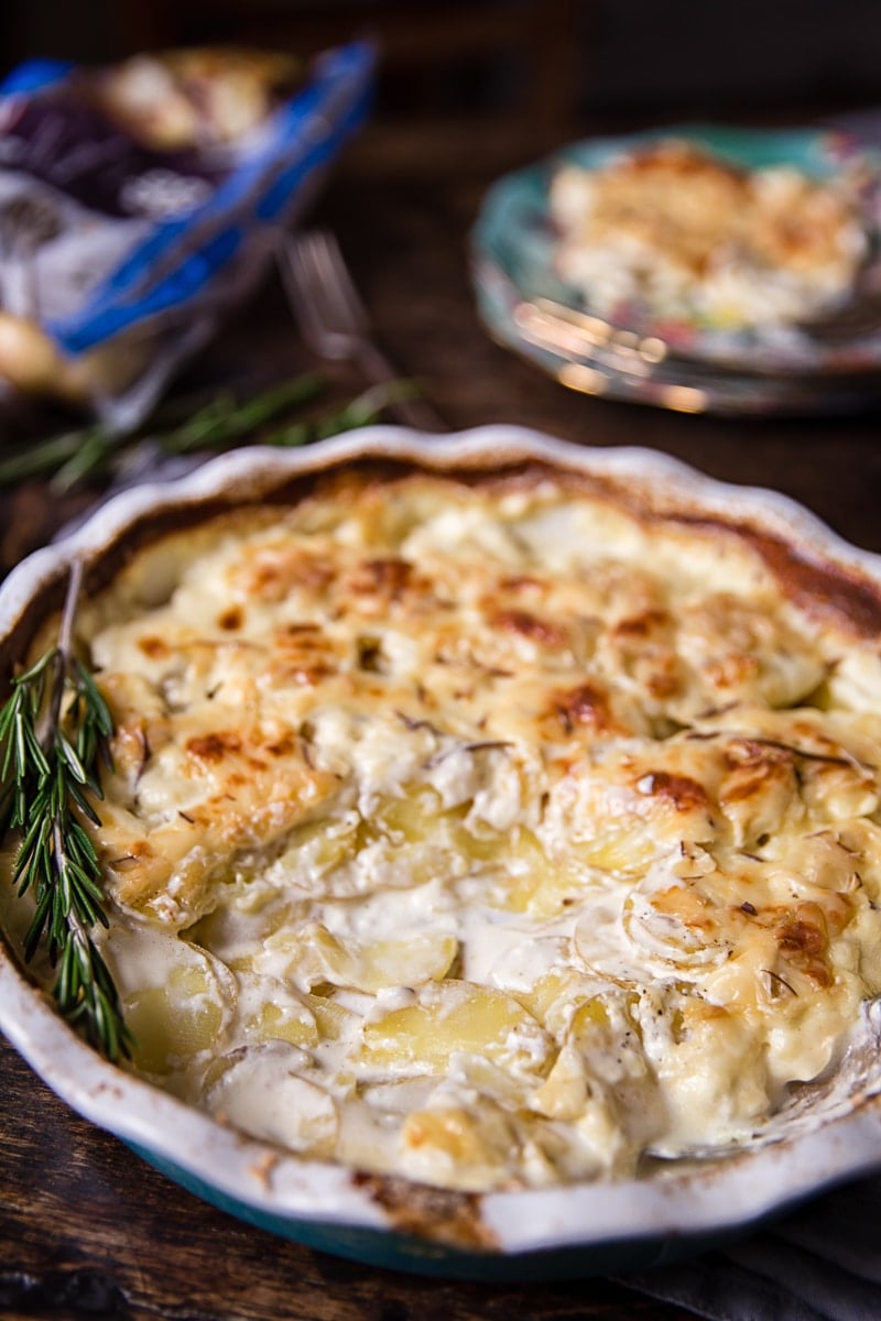 Baking dish with rosemary potatoes au gratin and a spoonful remove
