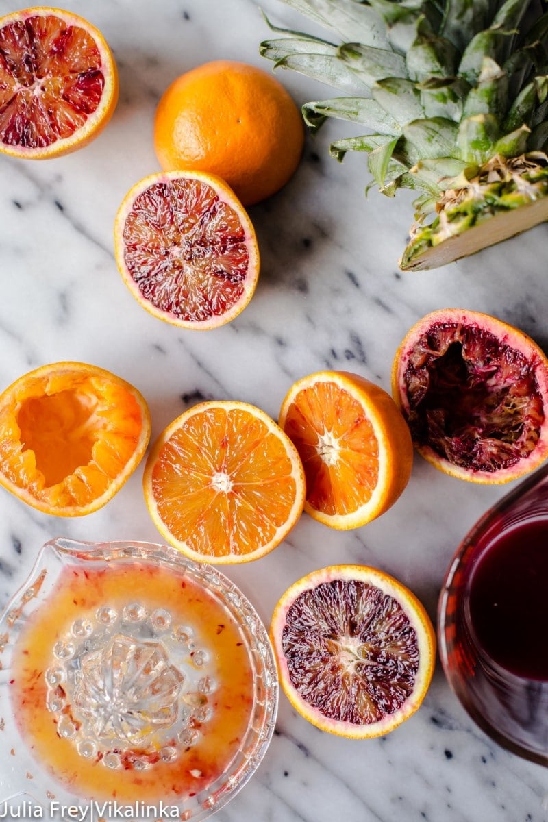 orange and blood oranges cut in half, a juice and a cut pineapple