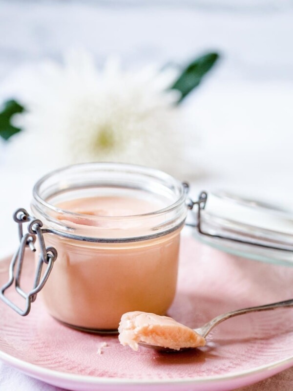 Rhubarb curd in a glass container with a spoon