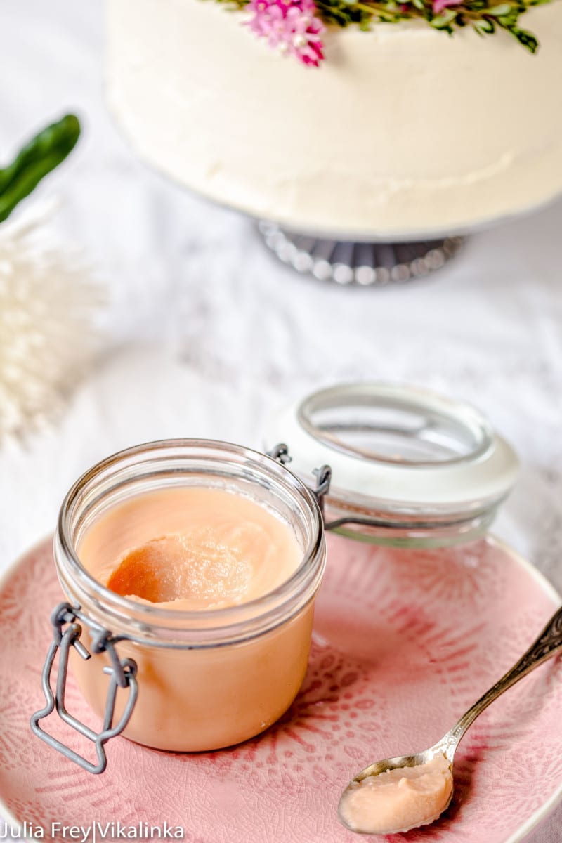 Rhubarb curd in a container on a plate with spoonful removed
