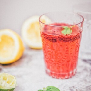 Side view of blackberry basil lemonade in a clear glasss