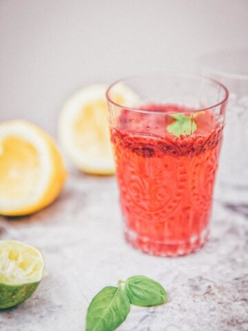 Side view of blackberry basil lemonade in a clear glasss