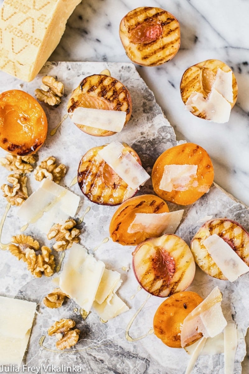 Stone fruit on a marble slab with walnuts and cheese shavings