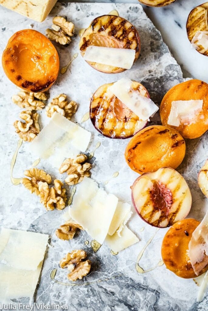 Top down view of grilled fruit with cheese and walnuts on marble slab