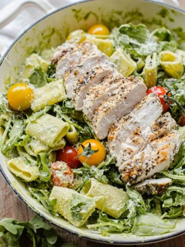 Pesto Pasta with sliced grilled chicken, cherry tomatoes and arugula.