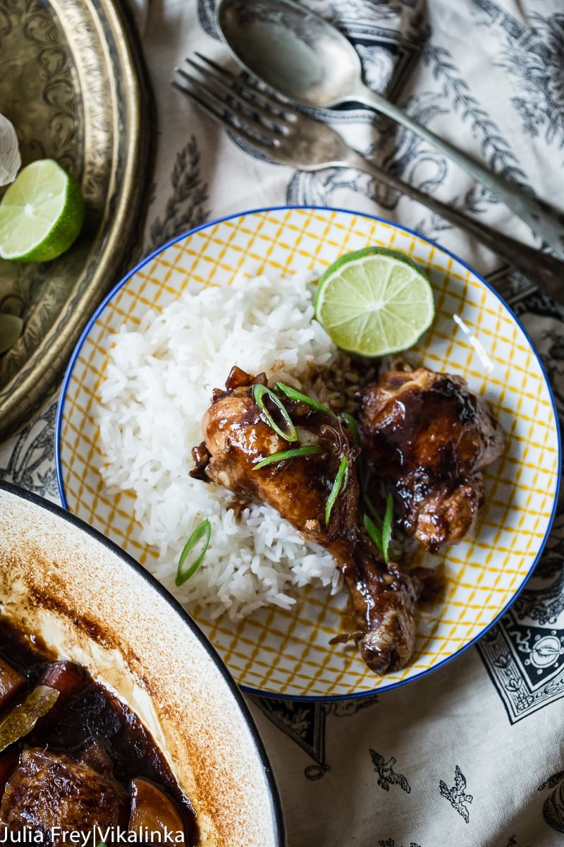 Plate of rice with chicken on top alongside lime slice