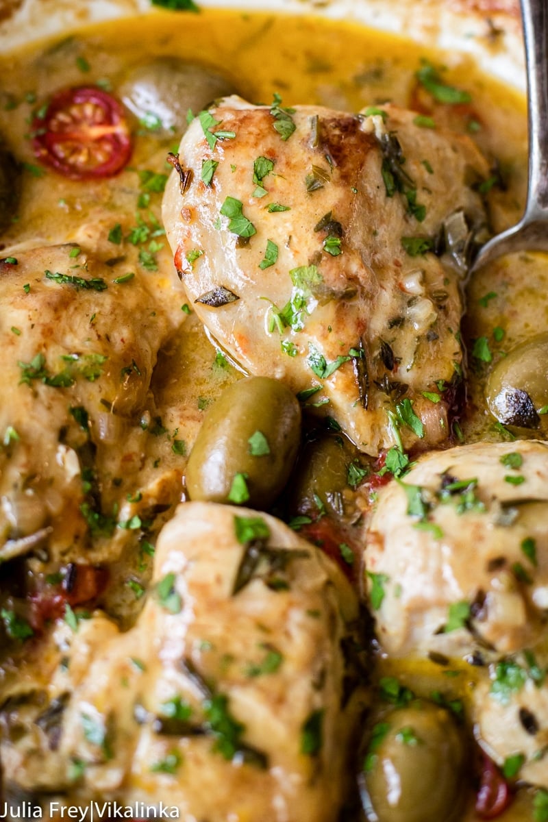 close up of a chicken dishes with olives and tomatoes in a light sauce