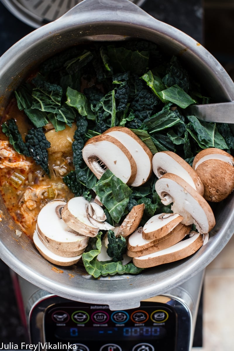 sliced mushrooms and kale in a pot of soup