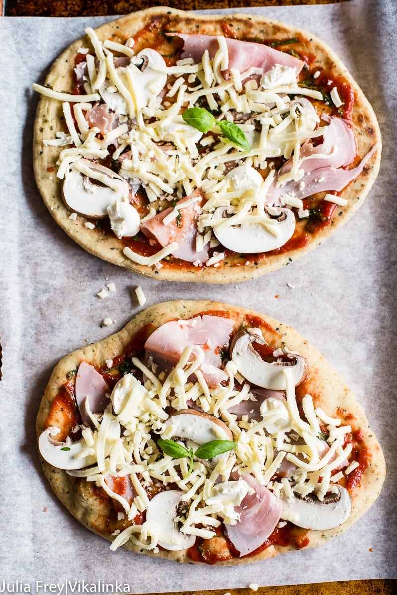 Two unbaked pizzas on a baking sheet