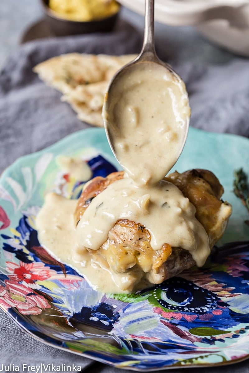 a piece of chicken with creamy sauce being spooned over it