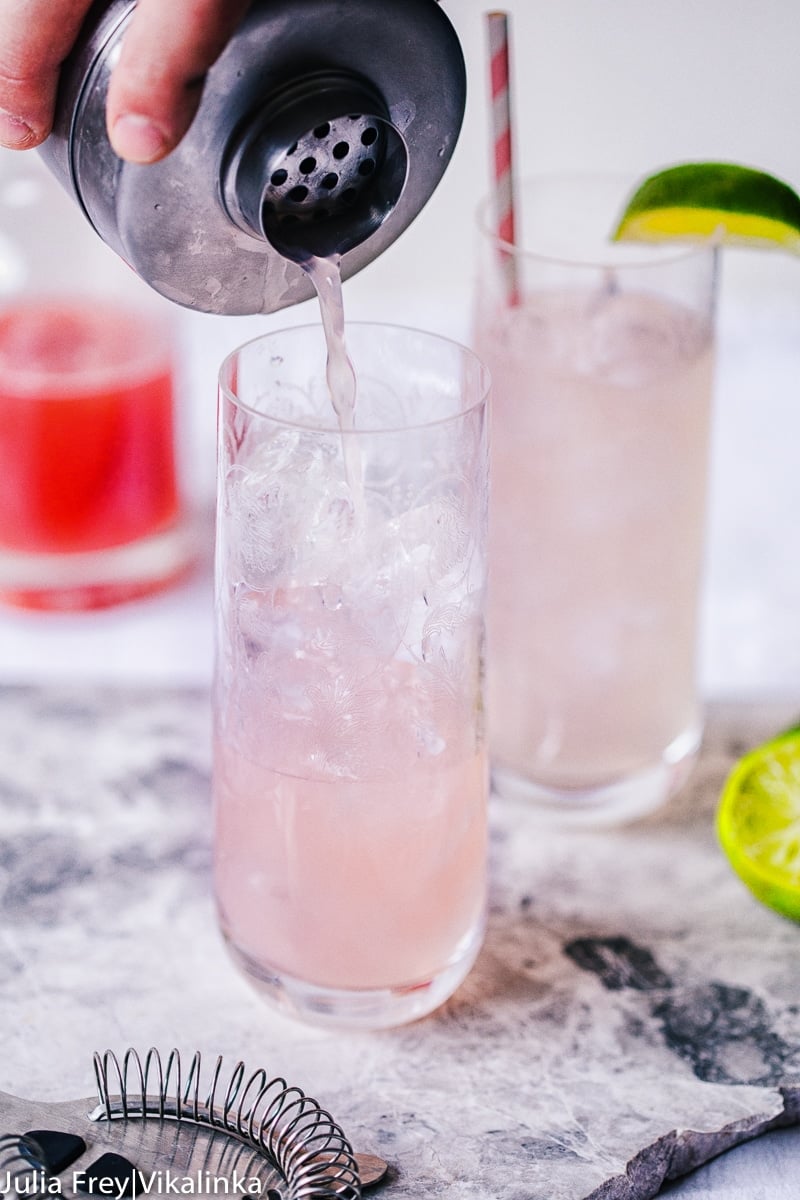 Cocktail shaker pouring drink over ice