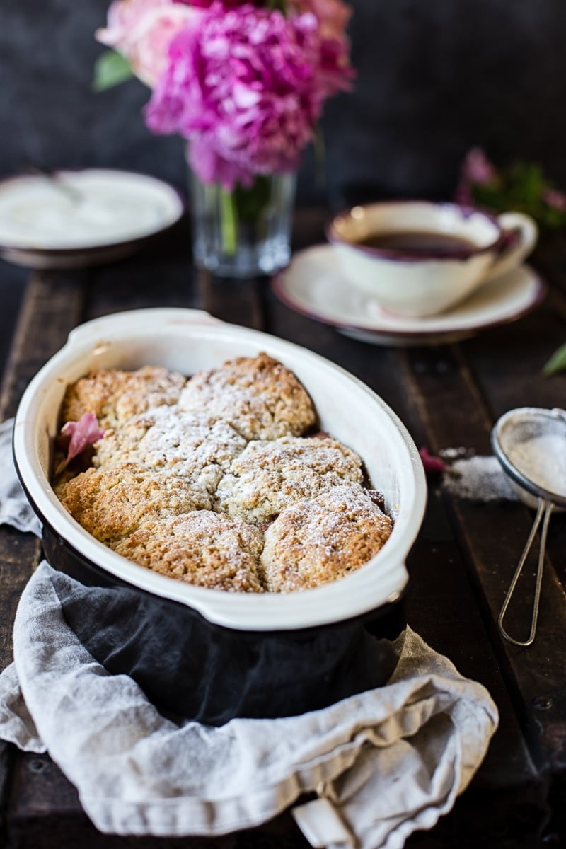 Rhubarb cobbler in a baking dish in front of tea and flowers