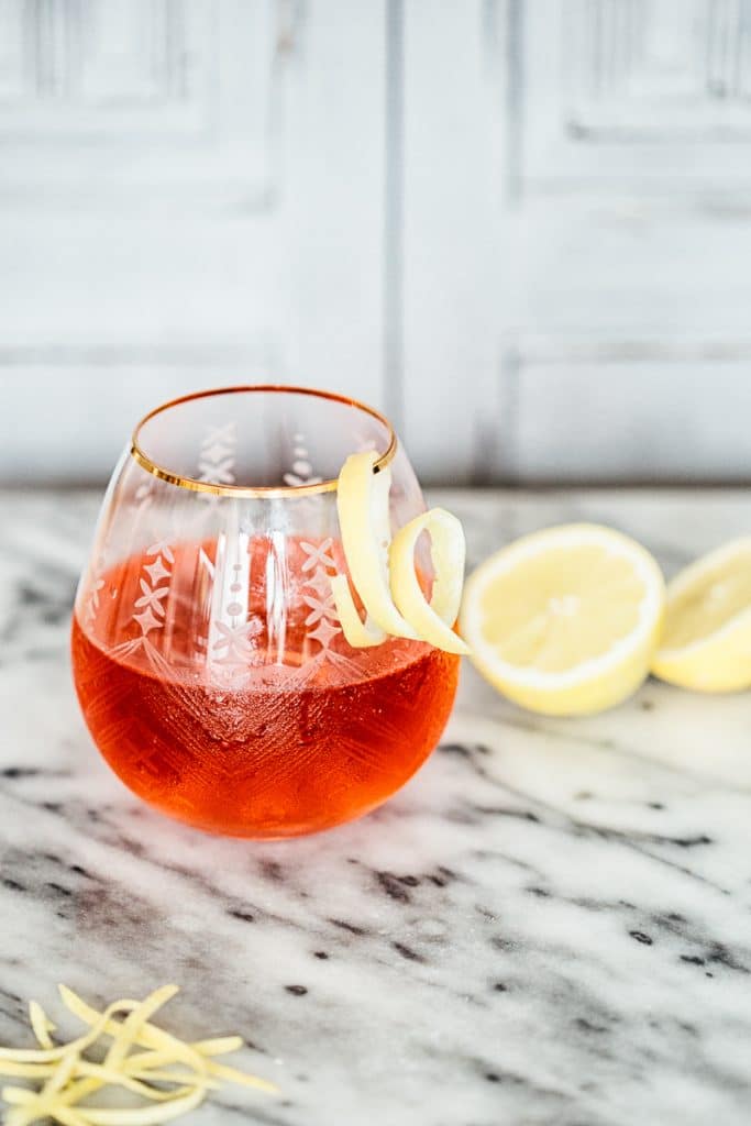 Side shot of Hibiscus and Lemon Gin and Tonic In a glass with a lemon swirl