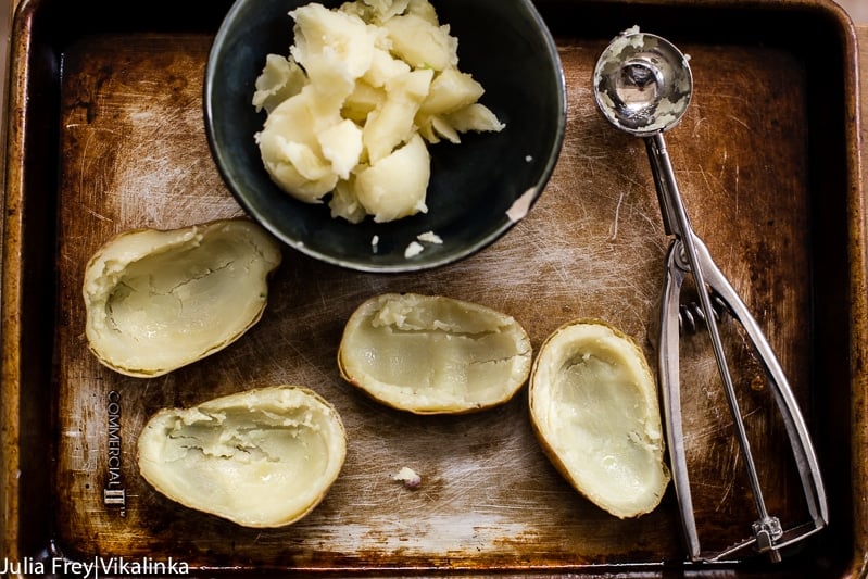 Baking sheet with cooked potatoes with insides scooped out