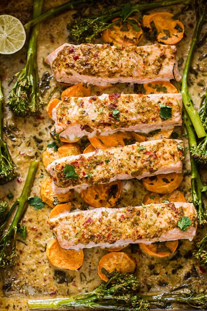 Baking tray with salmon on top of vegetables