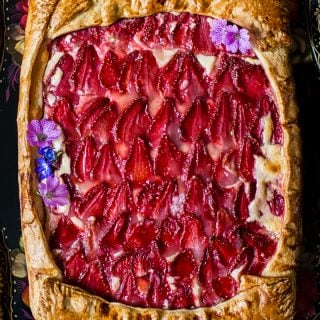 View of strawberry galette with pink flowers as decoration