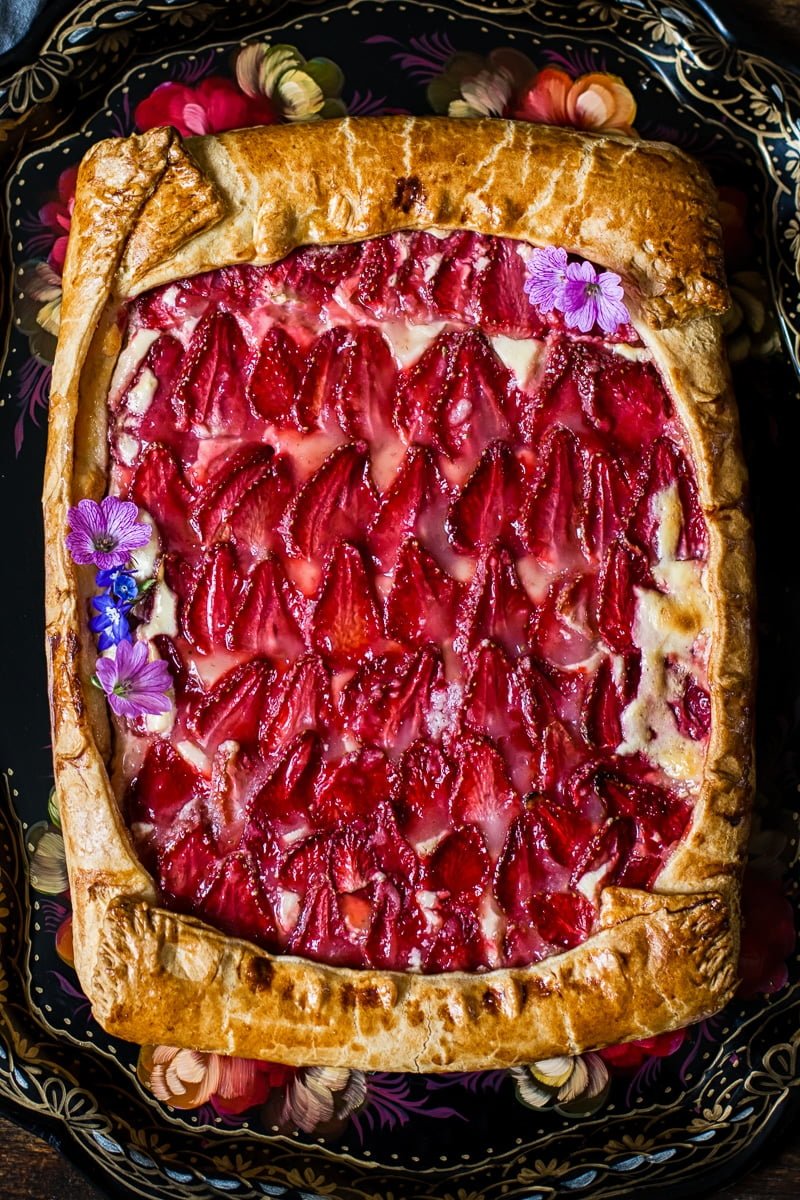 View of strawberry galette with pink flowers as decoration