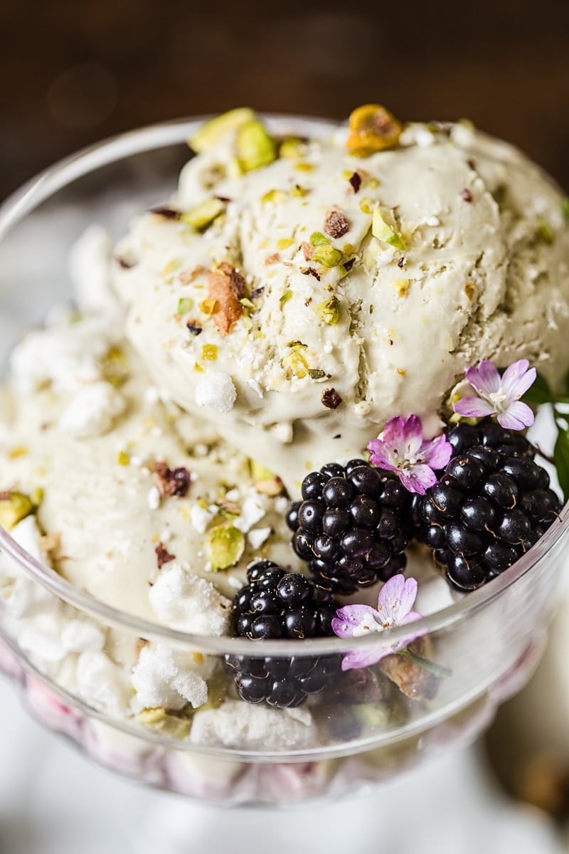 Glass dish with the pistachio ice cream Eton mess and three blackberries