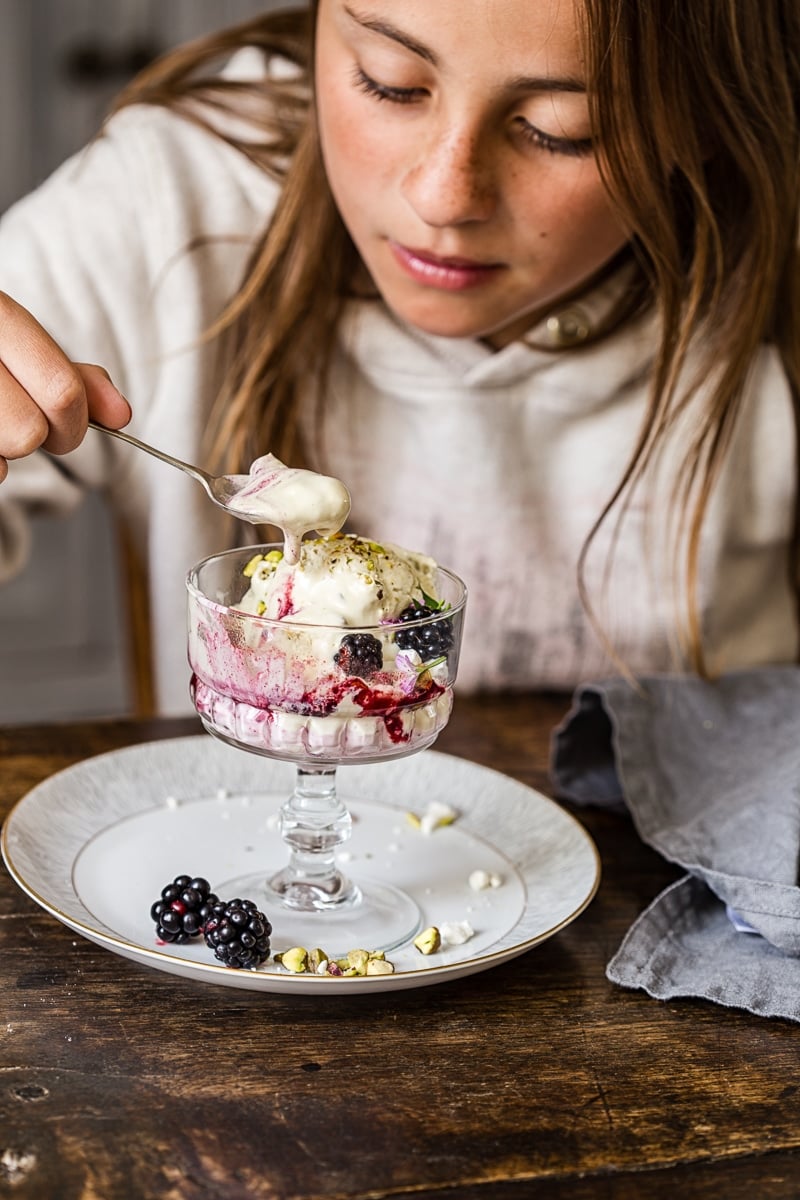 Girl eating the dessert from a glass dish