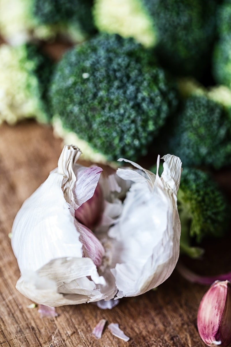 a head of garlic and broccoli in the background