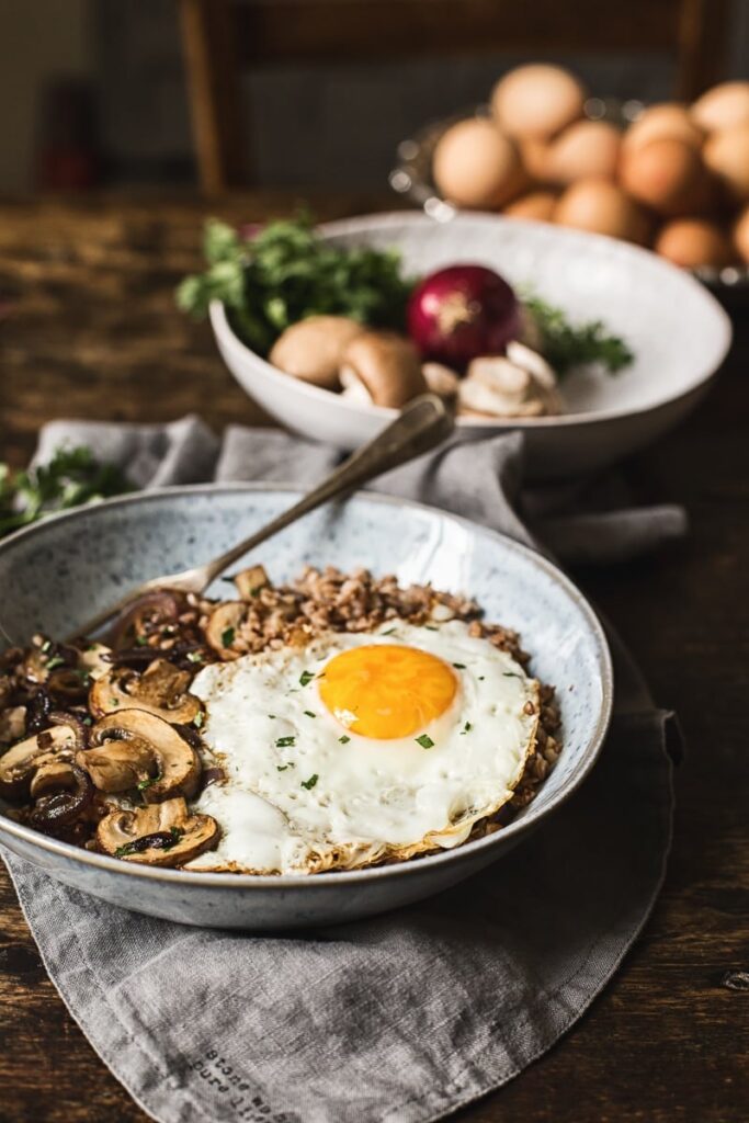 Buckwheat breakfast bowl with a fried egg in front of raw ingredients