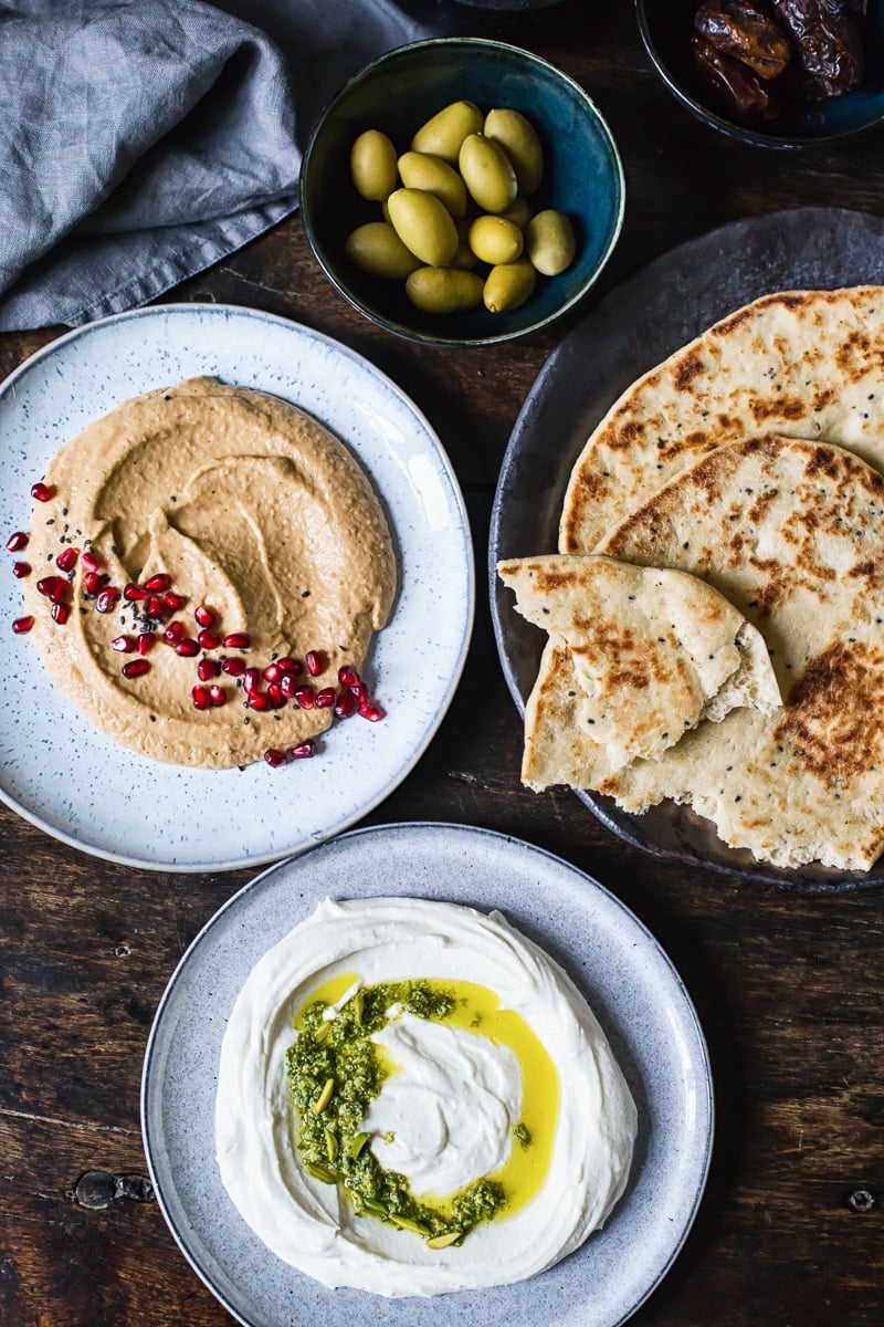 Whipped feta and ricotta dip with mint pistachio pesto on a table with other items