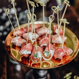 Herby Cheese Stuffed Dates Wrapped in Prosciutto on a cake stand