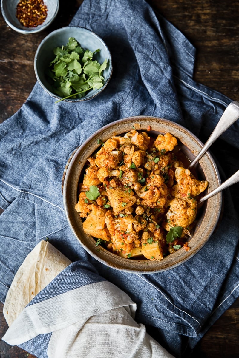 overhead shot of cauliflower and potato curry in a clay pot