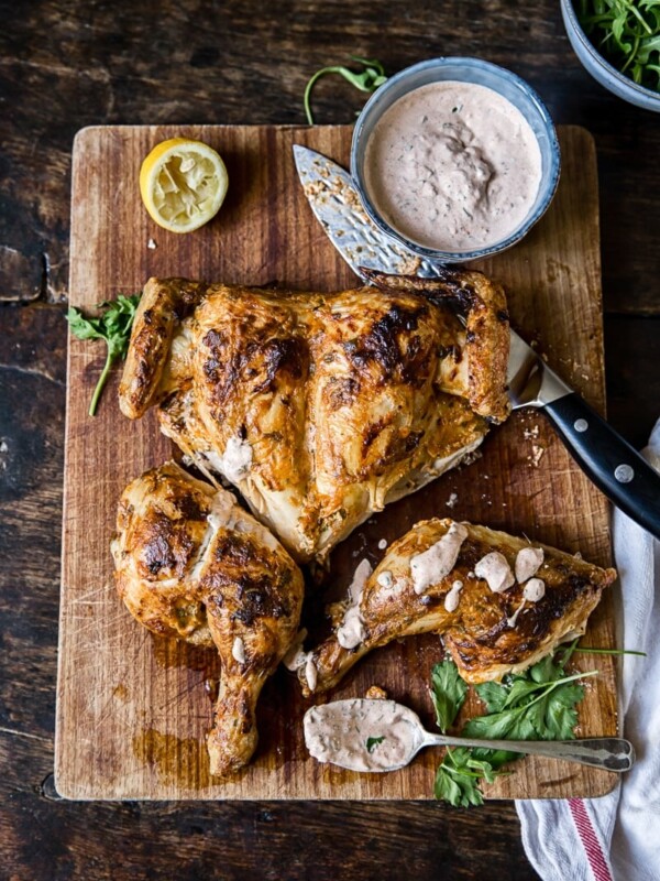Spatchcocked Chicken in Spicy Yogurt Sauce on a cutting board with knife