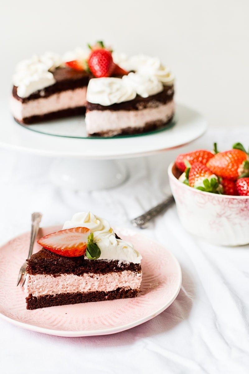Slice of chocolate strawberry cake on a plate with strawberries