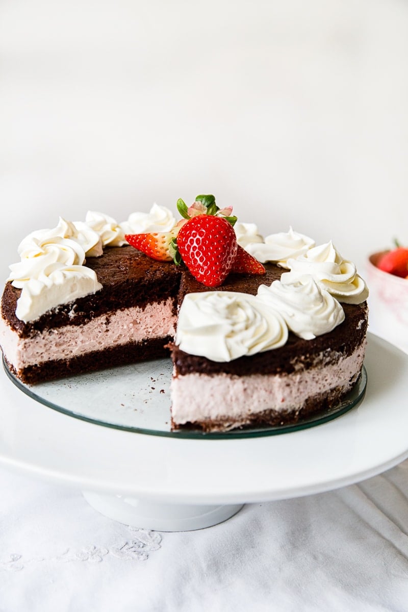 Chocolate strawberry cake on a stand with slice removed