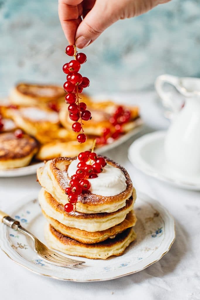 hand adding berries to stack of pancakes