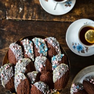 Top down of a plate of Chocolate Madeleines with cups of tea