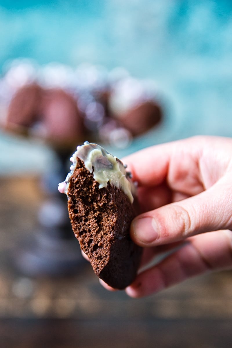 Chocolate Madeleines held by a hand with bite taken out