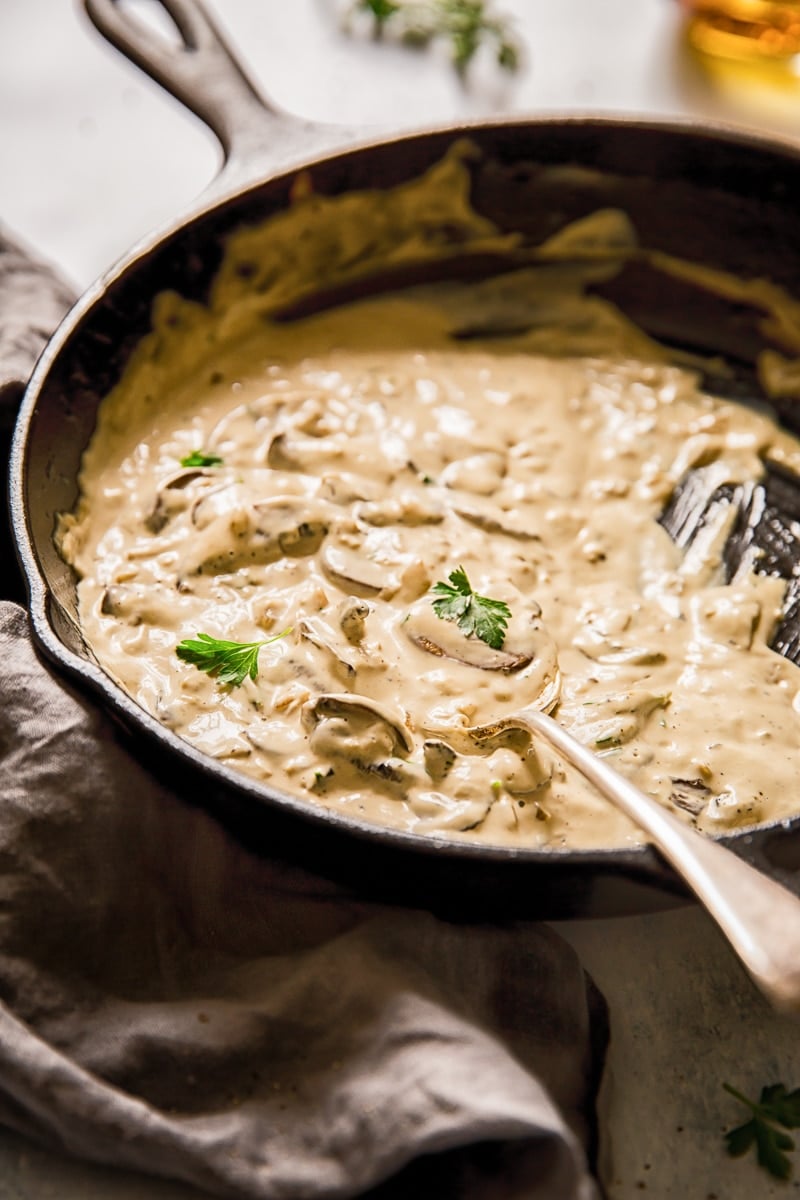 Side view of spoon in a pan with cognac sauce with mushrooms