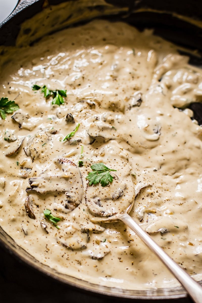Close up view of spoon scooping creamy cognac mushroom steak sauce in a pan