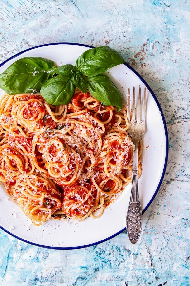 Plate of spaghetti covered in sauce and a garnish of basil