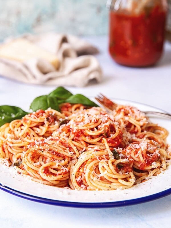 Plate of spaghetti with sauce with jar of sauce in the background