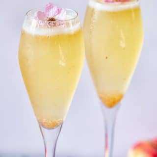 Two glasses with Elderflower Peach Bellini and flower garnish