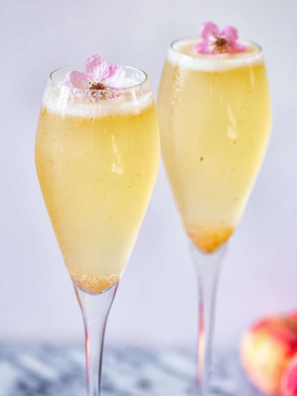 Two glasses with Elderflower Peach Bellini and flower garnish