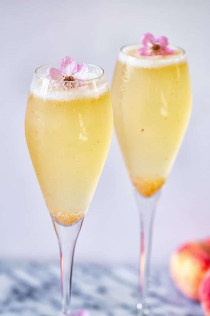 Two glasses with Elderflower Peach Bellini and flower garnish