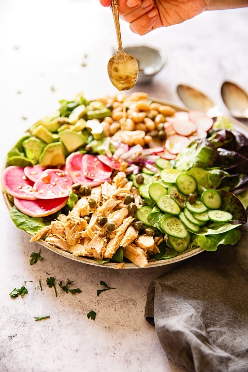 Healthy tuna salad with a spoon drizzling dressing