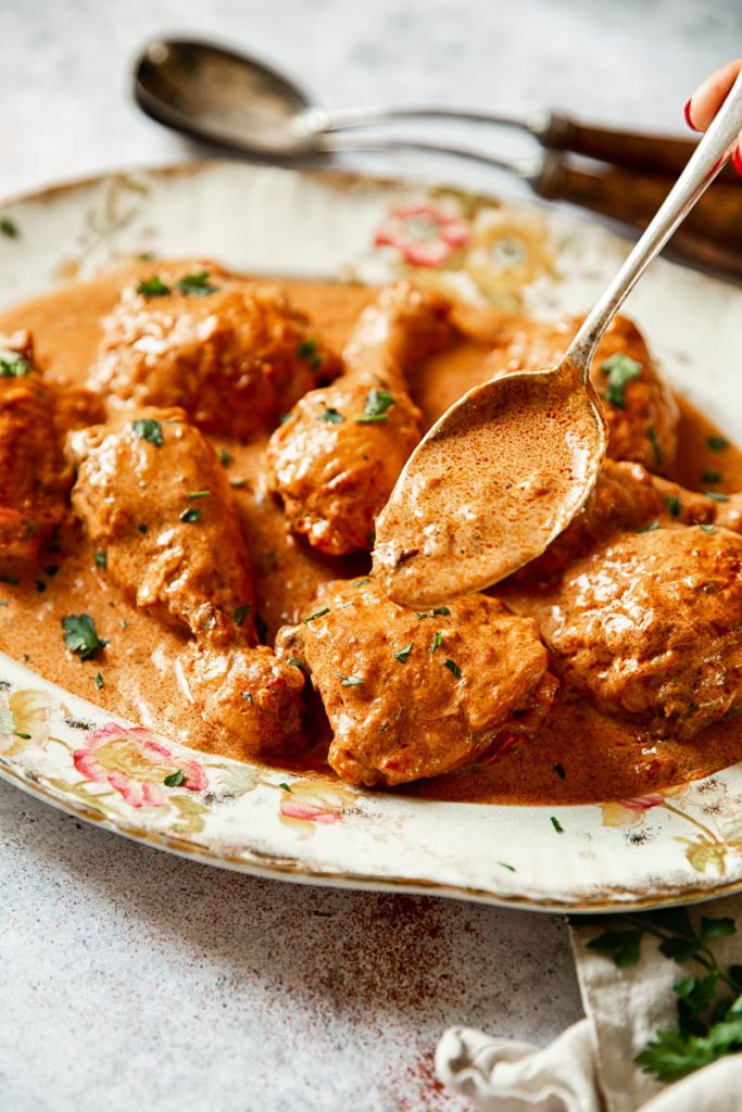 A spoon pouring the red sauce over the dish