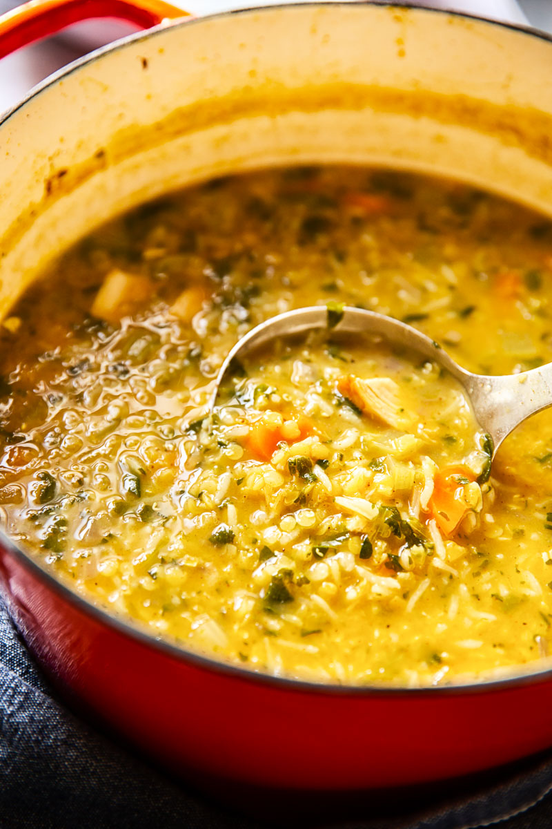 Close up of a ladle removing a serving with rice and chicken