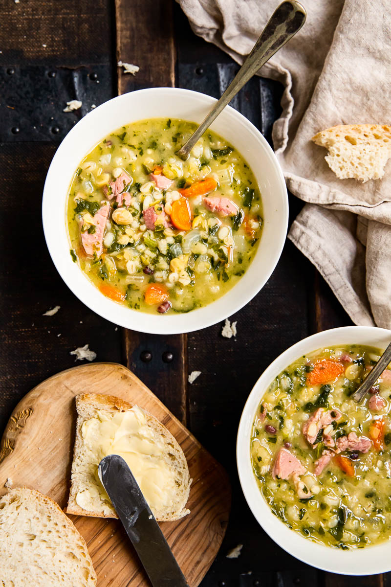 top down view of two bowls of Ham and Pea Soup with bread and butter